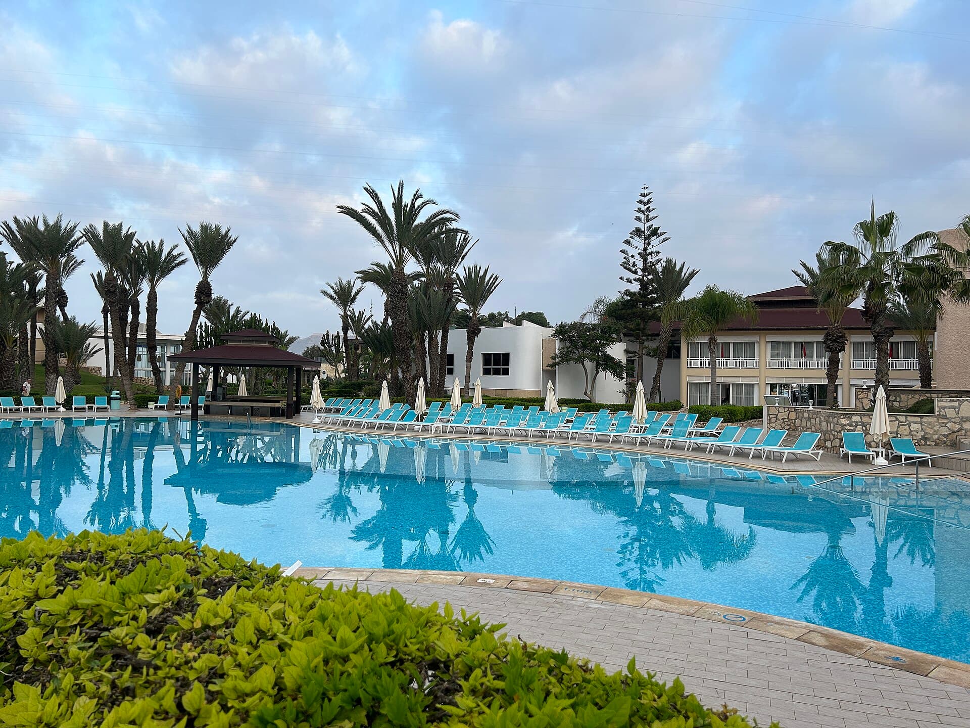 Sparkling clean pool in soft morning light, lined with empty lounge chairs — ready for opening day
