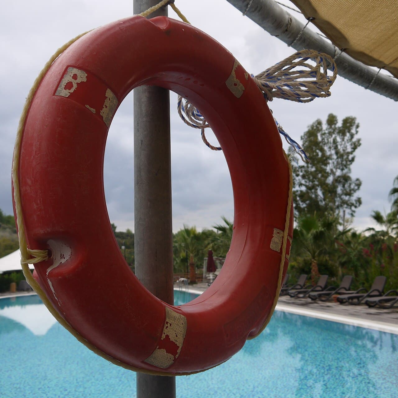 Orange lifebuoy mounted beside a swimming pool