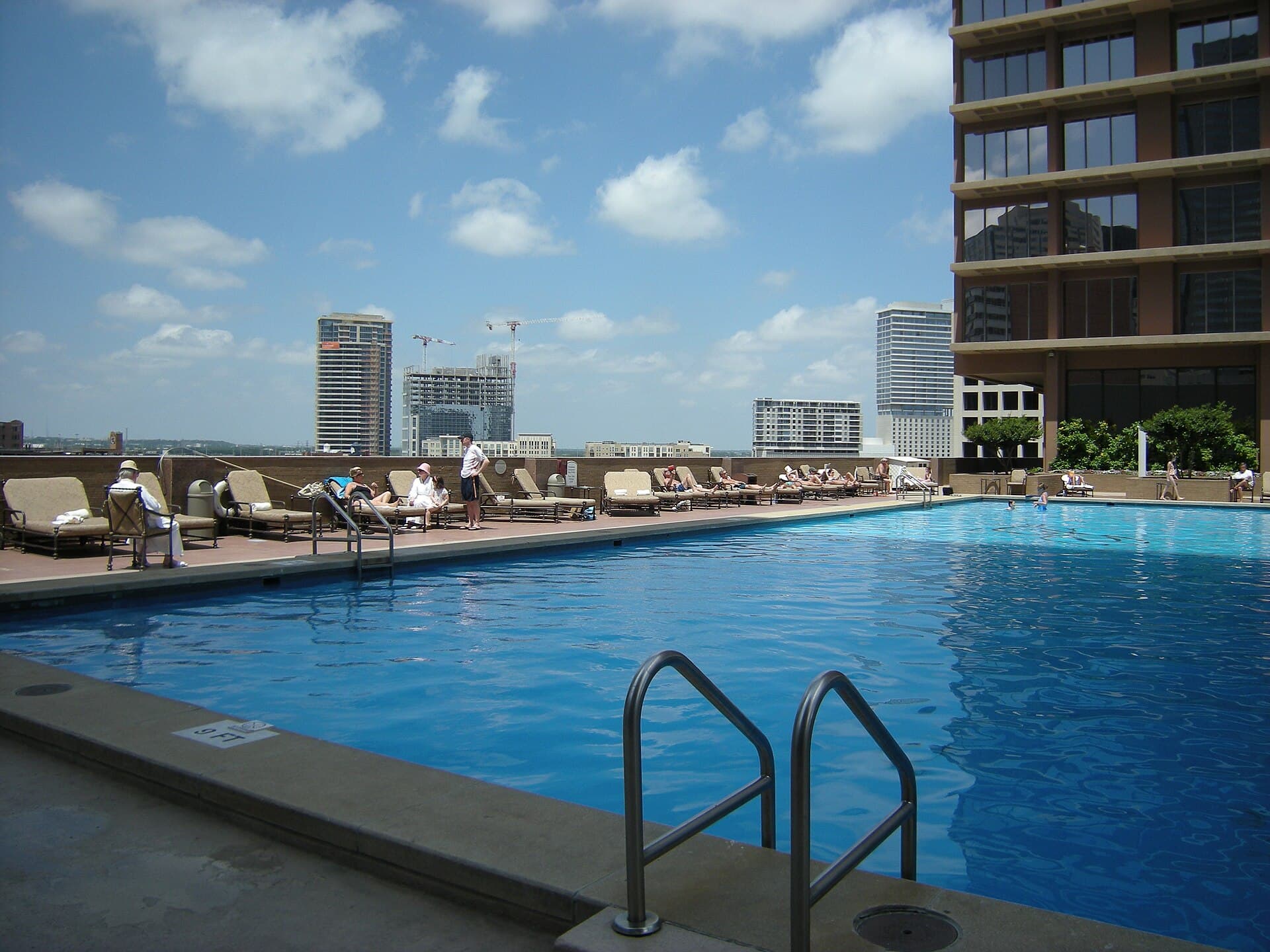 Large rooftop amenity pool with loungers and skyline — the shared aquatic lifestyle of many DFW communities